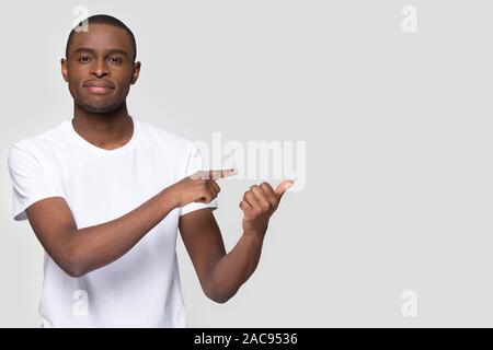 Bello African American uomo dita di puntamento a parte a copiare lo spazio, guardando la telecamera, cliente soddisfatto cliente presentando prodotto, negozi vendita, sp Foto Stock