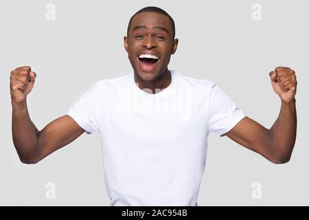Felice giovane americano africano uomo con sani sorriso bianco per celebrare il successo, urla di gioia, eccitato da una buona notizia, vittoria, successo, guardando Foto Stock