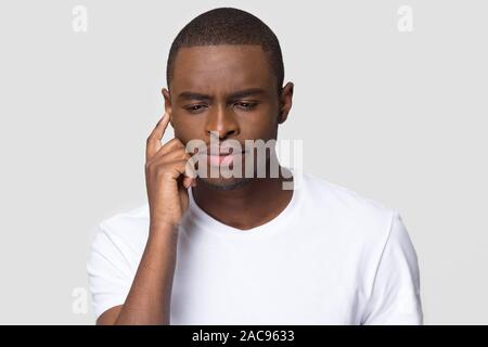 Perplesso African American uomo cercando di ricordare informazioni importanti, pensieroso pensieroso giovane maschio toccando tenendo premuto il dito sul tempio, guardare confusa, Foto Stock