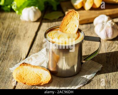 Semplice dieta non è cibo grasso, una piccola porzione di minestra in crema purè di patate e cavolo cappuccio in una tazza di metallo, crostini. Vista laterale, il fuoco selettivo dayligh Foto Stock