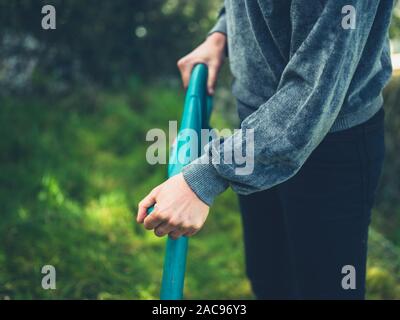 Una giovane donna è il taglio del prato utilizzando un decespugliatore di erba Foto Stock