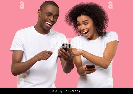 Emozionato americano africano giovane utilizzando il telefono cellulare e la lettura di buone notizie Foto Stock