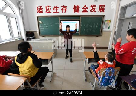(191202) -- MUDANJIANG, Dicembre 2, 2019 (Xinhua) -- Zhang Na interagisce con gli studenti di una scuola di educazione speciale in Mudanjiang, a nord-est della Cina di Provincia di Heilongjiang, nov. 27, 2019. Zhang Na, 38, ha servito come un insegnante di musica in una scuola di educazione speciale per quindici anni. La maggior parte dei suoi studenti sono bambini con disabilità intellettuale. 'My gli studenti amano la musica e mostrano una grande sensibilità per la musica. Vorremmo riprodurre musica rilassante per aiutarli con le emozioni negative", ha detto. La scuola di educazione speciale, con una storia di oltre 60 anni, attualmente ha circa 100 studenti. (Xinhua/Wang Jianwei) Foto Stock