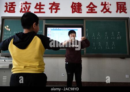(191202) -- MUDANJIANG, Dicembre 2, 2019 (Xinhua) -- Zhang Na comunica con gli studenti di una scuola di educazione speciale in Mudanjiang, a nord-est della Cina di Provincia di Heilongjiang, nov. 27, 2019. Zhang Na, 38, ha servito come un insegnante di musica in una scuola di educazione speciale per quindici anni. La maggior parte dei suoi studenti sono bambini con disabilità intellettuale. 'My gli studenti amano la musica e mostrano una grande sensibilità per la musica. Vorremmo riprodurre musica rilassante per aiutarli con le emozioni negative", ha detto. La scuola di educazione speciale, con una storia di oltre 60 anni, attualmente ha circa 100 studenti. (Xinhua/Wang Jianwei) Foto Stock