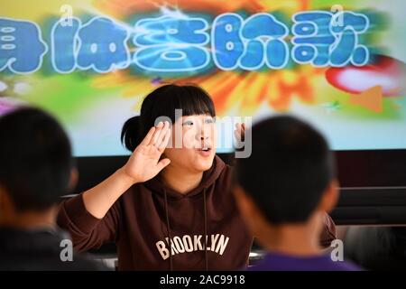 (191202) -- MUDANJIANG, Dicembre 2, 2019 (Xinhua) -- Zhang Na dà una classe di musica in una scuola di educazione speciale in Mudanjiang, a nord-est della Cina di Provincia di Heilongjiang, nov. 27, 2019. Zhang Na, 38, ha servito come un insegnante di musica in una scuola di educazione speciale per quindici anni. La maggior parte dei suoi studenti sono bambini con disabilità intellettuale. 'My gli studenti amano la musica e mostrano una grande sensibilità per la musica. Vorremmo riprodurre musica rilassante per aiutarli con le emozioni negative", ha detto. La scuola di educazione speciale, con una storia di oltre 60 anni, attualmente ha circa 100 studenti. (Xinhua/Wang Jianwei) Foto Stock