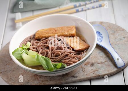 Porzione di Soba noodle soup con fettine di tofu e foglie di cavolo cinese Foto Stock