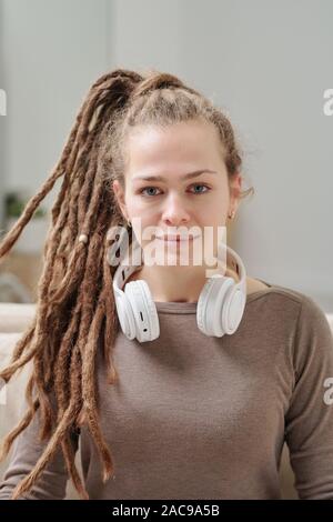 Bella ragazza sorridente in pullover con cuffie intorno al collo Foto Stock