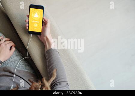 Panoramica della giovane femmina lato con lo smartphone seduta sul lettino Foto Stock