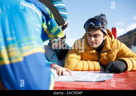 Tre gli snowboarder di esplorare la mappa in località invernale nel pomeriggio Foto Stock