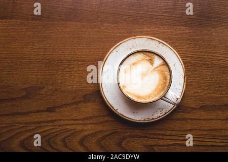 Il Cappuccino in tazza rustico e piatto su un marrone coffee shop tabella. Vista superiore, piatto laici. Foto Stock