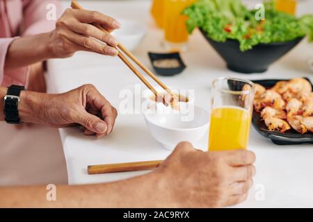 Le mani della donna matura mettendo la deliziosa big i gamberi in una ciotola di suo marito a cena Foto Stock