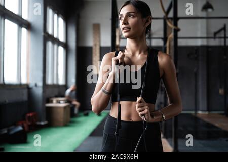 Montare e donna sana in piedi alla palestra con corda da salto. Sportive riposo dopo l'allenamento. Foto Stock