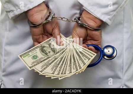 Medico con banconote di dollari e manette Foto Stock