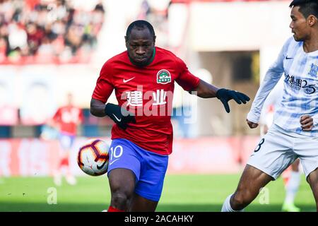 Calcio camerunese player Bassogog Cristiana di Henan Jianye F.C., sinistra, protegge la sfera durante la trentesima partita di calcio cinese Associazione Super League (CSL) contro Guangzhou R&F nella Città di Zhengzhou, centrale cinese della provincia di Henan, 1 dicembre 2019. L Henan Jianye sconfitto Guangzhou R&F con 1-0. Foto Stock