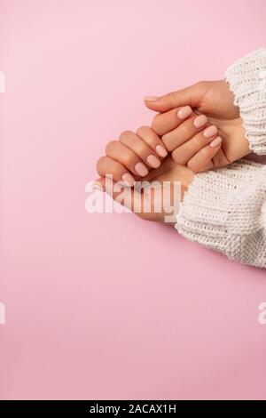 Primo piano delle mani belle, UNGHIE MANICURE delicato su sfondo rosa. Attenzione, bellezza, spa, salone concetto, vista dall'alto, spazio di copia Foto Stock