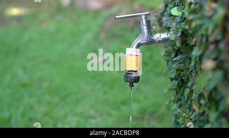 Rubinetto esterno di gocciolamento dell'acqua. Salvare o acqua calda estate concetto. Foto Stock