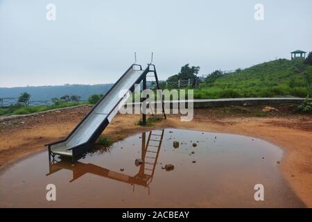 In prossimità di una diapositiva per bambini nel Parco Ecologico di Cherrapunjee con acqua nel suolo e delle colline circostanti e sky in vista, messa a fuoco selettiva Foto Stock