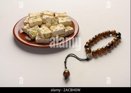 Orientale torrone arabo dolcezza con pistacchi su una piastra di ceramica su uno sfondo luminoso. Close up Foto Stock