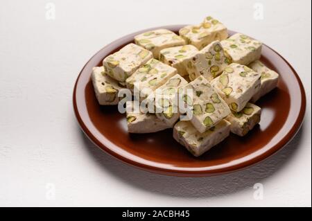 Orientale torrone arabo dolcezza con pistacchi su un marrone piastra ceramica su uno sfondo luminoso Foto Stock