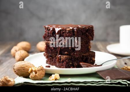 Spugnoso di cioccolato brownie torte con noci e cioccolato fuso topping su una pila Foto Stock