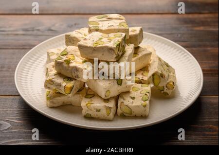 Orientale torrone arabo dolcezza con pistacchi su una piastra di ceramica su uno sfondo luminoso. Close up Foto Stock