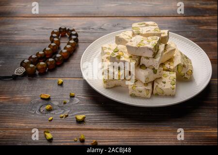 Orientale torrone arabo dolcezza con pistacchi su una piastra di ceramica su uno sfondo luminoso. Close up Foto Stock