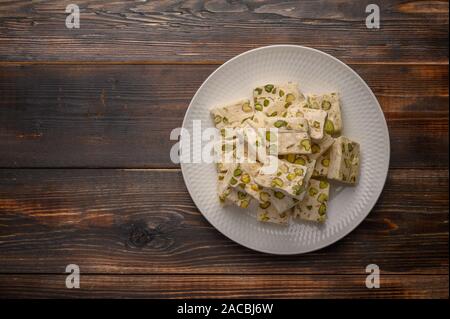 Orientale torrone arabo dolcezza con pistacchi su una piastra di ceramica su uno sfondo luminoso. Vista superiore Foto Stock