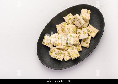 Orientale torrone arabo dolcezza con pistacchi su una piastra di ceramica su uno sfondo luminoso. Vista superiore Foto Stock