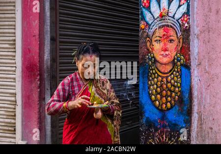 Devoto offre Prasad, religiosi cibo, per la verniciatura di una dea in corrispondenza di un muro di casa al Festival Darsain Foto Stock