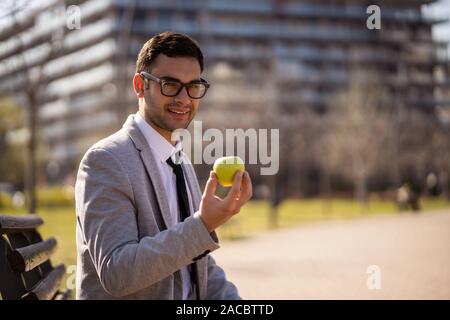 Giovane imprenditore è mangiare apple nel parco dopo il lavoro. Foto Stock