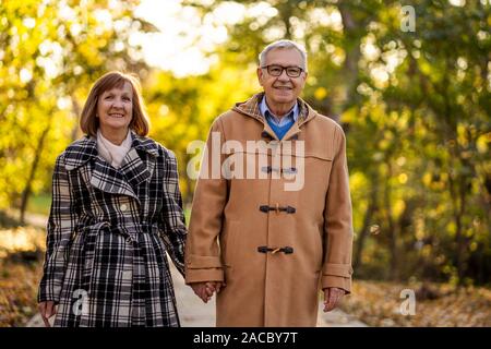 Romantico coppia senior è camminare nel parco in autunno. Foto Stock