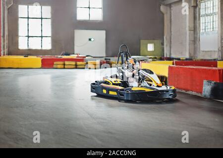 Intrattenimento per bambini in ambienti chiusi. Ragazza la guida go kart su pista. Uno stile di vita attivo. Foto Stock