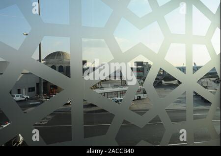 04.01.2014, Abu Dhabi, Emirati Arabi Uniti - Vista attraverso una finestra ornata nel terminal di partenza del piazzale dell'Aeroporto di Abu Dhabi. Foto Stock