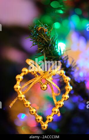 A forma di cuore decorazione di Natale appeso a una ben illuminata albero di Natale Foto Stock