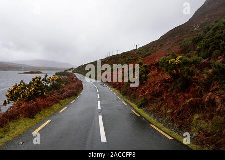 Svuotare strada che conduce al litorale e le isole in una distanza, moody cielo scuro con nuvole temporalesche Foto Stock