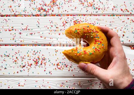 Uomo con morso ciambella su sfondo bianco Foto Stock