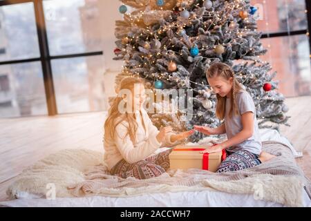 Contenti i bambini divertendosi e apertura presenta vicino albero di Natale. Foto Stock