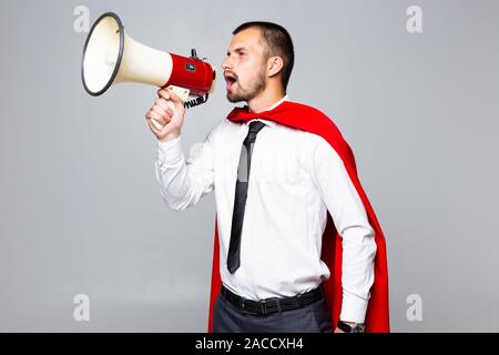 Imprenditore vestito come supereroe gridando da megafono Foto Stock