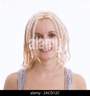 Sorridenti giovane donna bionda con dreadlocks e dente divario - studio headshot contro uno sfondo bianco Foto Stock