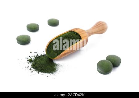Organic chlorella e spirulina in polvere e pillole in una paletta di legno isolato su bianco Foto Stock