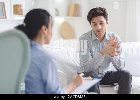 Stressante uomo emotivamente a psicoterapeuta sessione Foto Stock