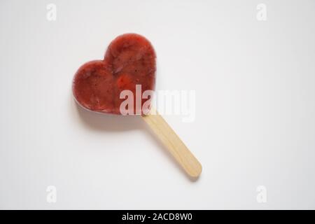 A forma di cuore in casa berry smoothie di frutta ghiaccioli o per lecca-lecca di ghiaccio o ghiaccio pop su sfondo bianco Foto Stock