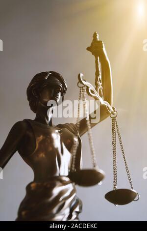 Signora giustizia o justitia bendati azienda di figurine di bilance di precisione - diritto e simbolo legale - con i raggi del sole perdite di luce Foto Stock