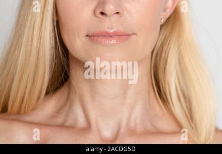 Bella donna matura con collo rugoso e sfondo grigio Foto Stock
