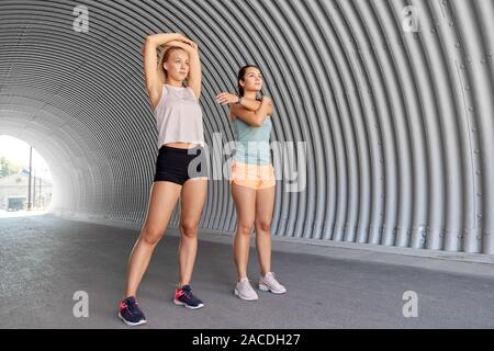 Le donne con fitness trackers stretching all'aperto Foto Stock