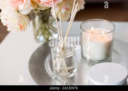 Aroma diffusore reed, candela e fiori sul tavolo Foto Stock