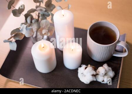 Candele, tè e rami di eucalipto su tavola Foto Stock