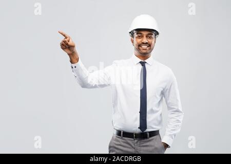 Indiano architetto maschio nel casco mostrando qualcosa di Foto Stock