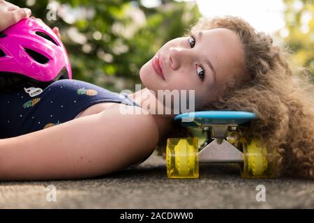 Ragazza distesa su skateboard Foto Stock