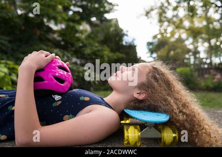 Ragazza distesa su skateboard Foto Stock